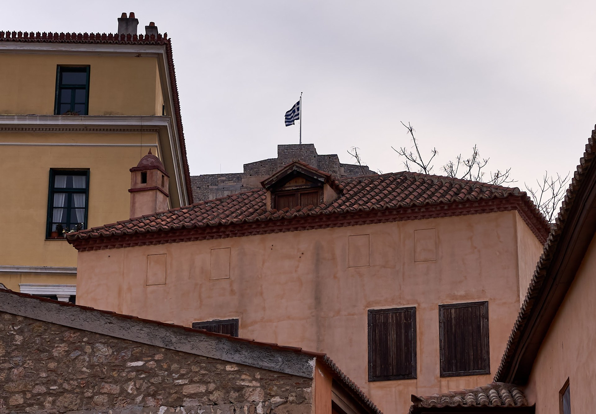 Shtëpi tradicionale në Plakë të Athinës, me muret e Akropolit në sfond