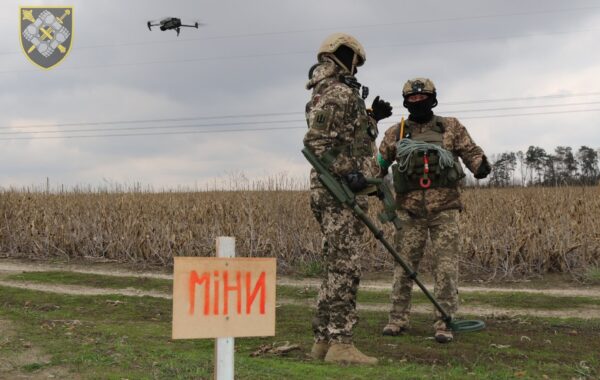 Ushtarë ukrainas të deminimit në një fushë me tabelë paralajmëruese për mina