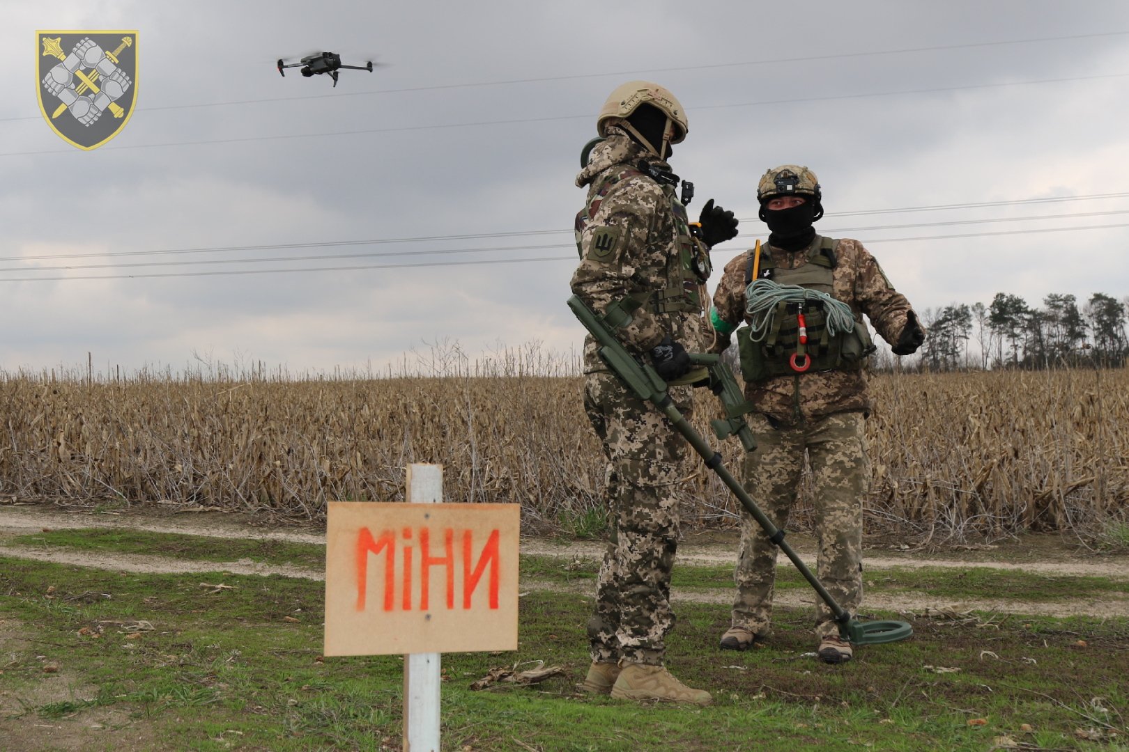 Ushtarë ukrainas të deminimit në një fushë me tabelë paralajmëruese për mina